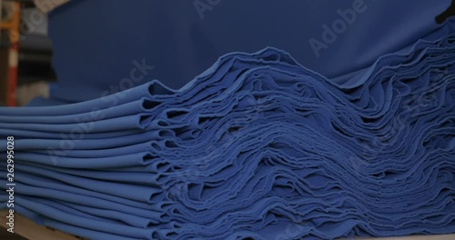 The garment factory takes a sample of a roll of blue fabric checking the quality of the roll checking on the machine the roll of fabric is unwound fully. Concept of: Checking quality, New fabric.