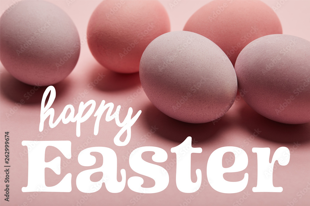 painted pink eggs on pink surface with white happy Easter lettering painted pink eggs on pink surface with white happy Easter lettering