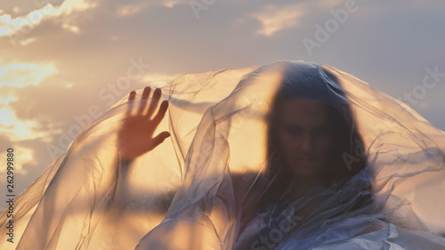 Portrait Of A Young Woman Feeling Her Human Identity Behind Plastic Foil At Sunset. photo
