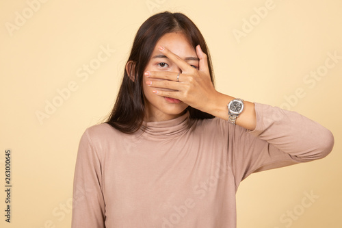 Beautiful young Asian woman peeking through fingers. © halfbottle