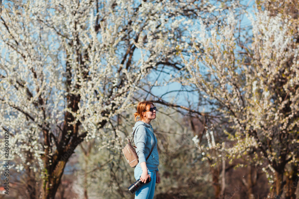 Girl photographer enjoying spring day in nature with a blooming cherry tree. Girl photographer enjoying spring day in nature with a blooming cherry tree.