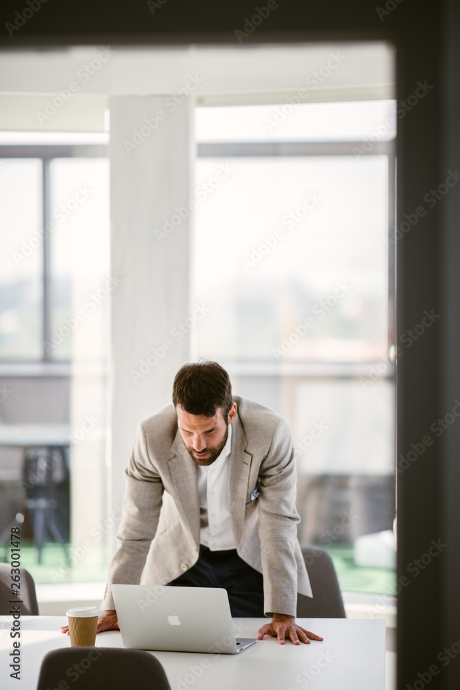 Businessman sitting looking at his laptop. Businessman working in the office on his laptop. Stylish businessman working on a project in the office thinking about future Businessman sitting looking at his laptop. Businessman working in the office on his laptop. Stylish businessman working on a project in the office thinking about future