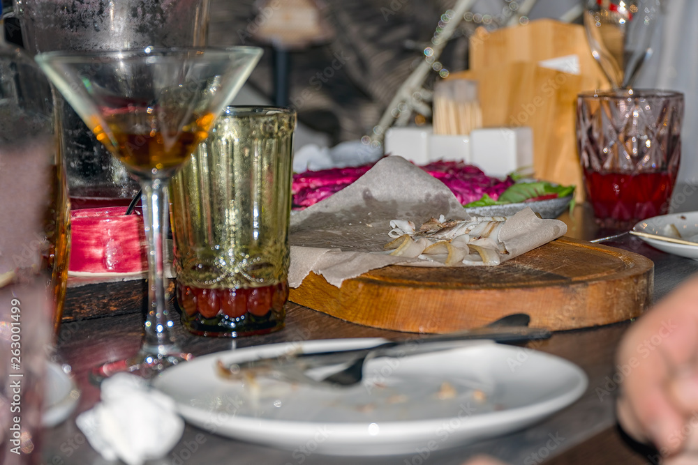 Untidy dirty table after party. Leftover food, empty glasses, wrinkled napkins