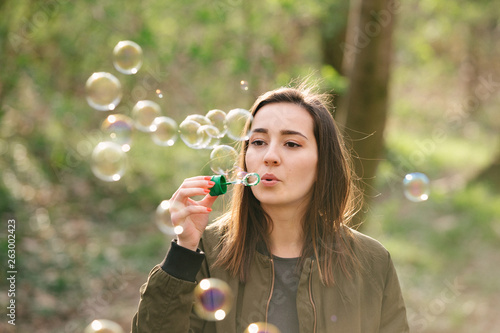 Young woman blowing soap bubbles in the woods.