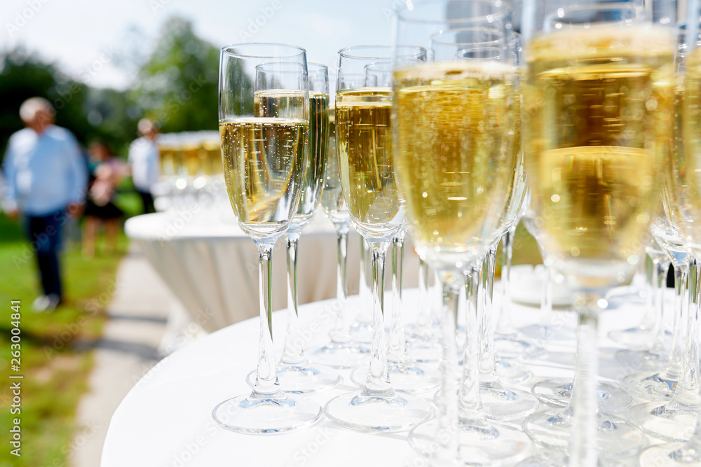 glasses of champagne stand on a white tablecloth on a table in the fresh air