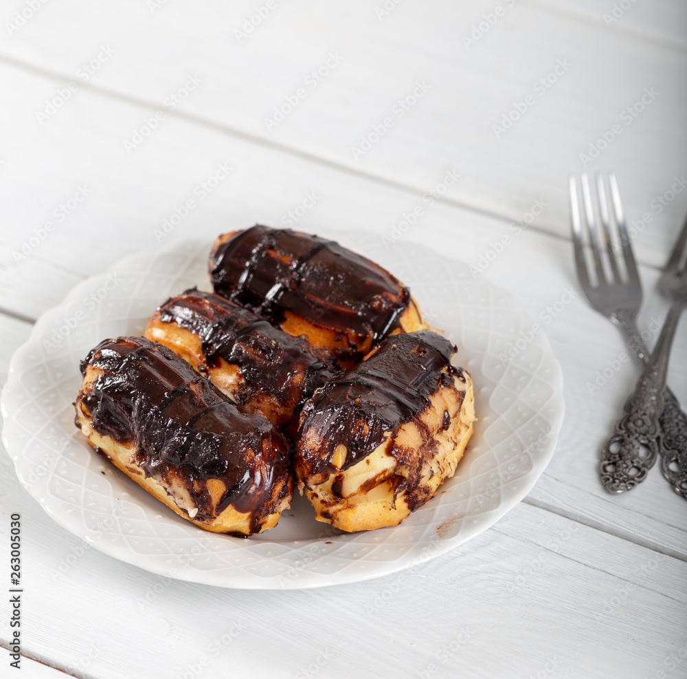 Ekler Pasta / Chocolate Donut in plate on white background. Ekler Pasta / Chocolate Donut in plate on white background.