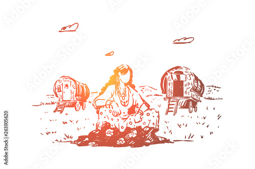 Young gypsy woman sitting in field, caravan on glade, free nation, wagons for traveling, female traveler rest on lawn photo