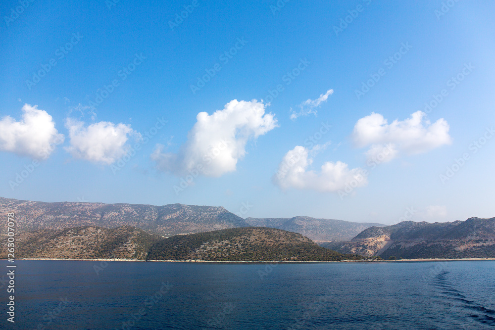 Fototapeta premium Mediterranean sea overlooking the mountains. Aerial top view of sea waves hitting rocks on the beach with turquoise sea water. Amazing rock cliff seascape in the coastline.