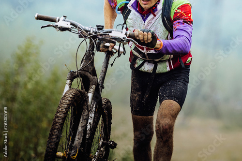 Fototapeta dirty cyclist climbing uphill with mountain bike on foot