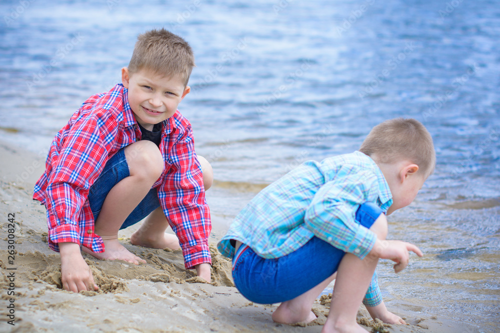 Kids boys playing on a beach near river with water and sand felling happy Kids boys playing on a beach near river with water and sand felling happy
