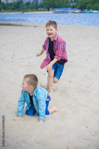 Kids boys playing on a beach near river with water and sand felling happy 