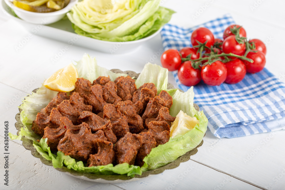 Turkish Food Cig Kofte with lemon, lettuce and parsley on silver plate Turkish Food Cig Kofte with lemon, lettuce and parsley on silver plate
