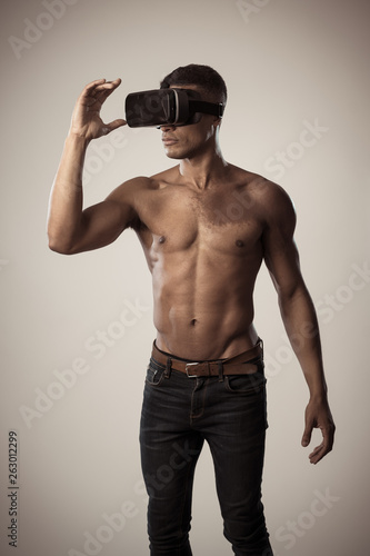 Sexy young african man wearing Virtual Reality headset exploring 3D experiences