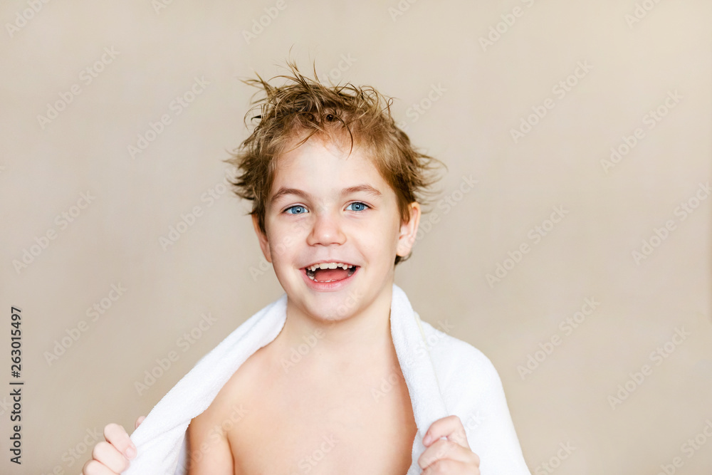 Blode caucasian boy after bath with wet hair and white towel on the shoulders laughing and showing ok hand sign over brown background Blode caucasian boy after bath with wet hair and white towel on the shoulders laughing and showing ok hand sign over brown background