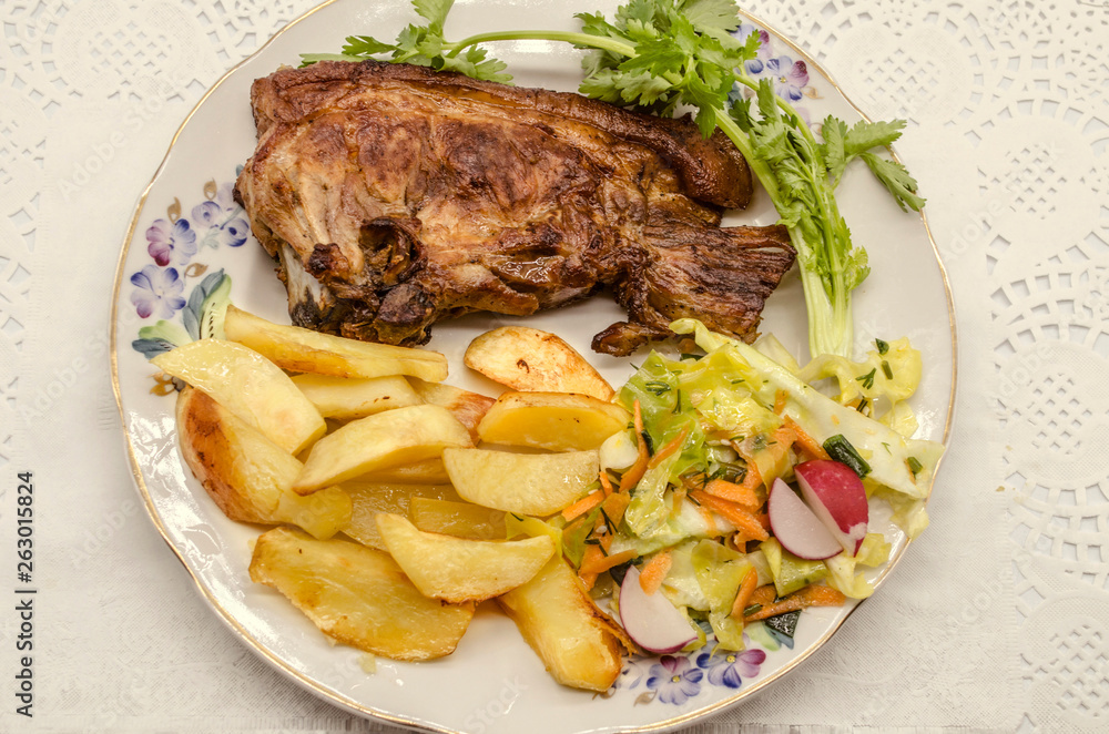  Barbecue and a sprig of cilantro with fried potatoes and cabbage salad, radishes and carrots seasoned with spices on a white porcelain plate