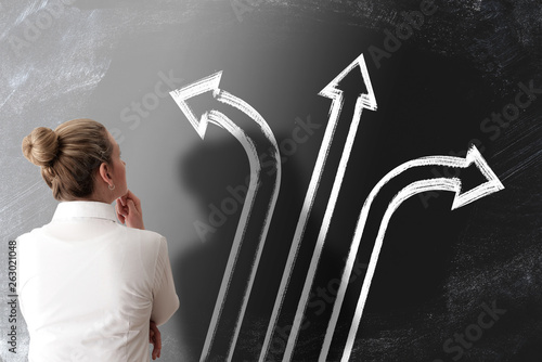 decision making concept with rear view of woman looking at chalkboard with arrows pointing in different directions