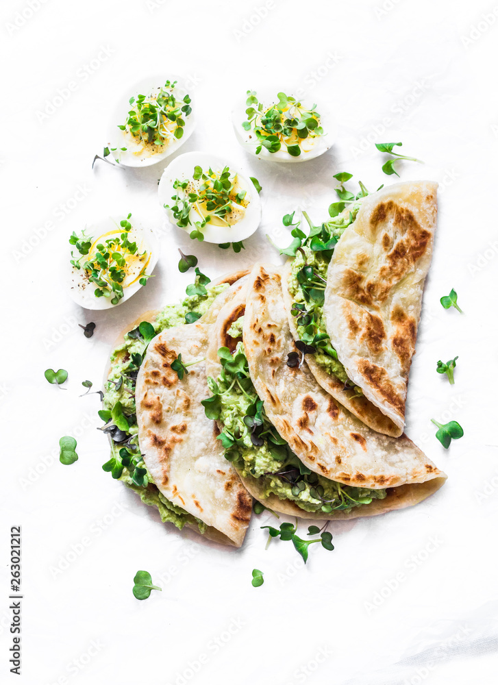 Avocado cream cheese micro greens quesadilla and boiled eggs on a light background, top view. Delicious healthy breakfast, snack, brunch. Flat lay