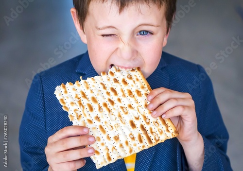 Cute Caucasian Jewish boy taking a bite from a traditional Jewish matzo unleavened bread. Jewish Passover Pesach concept image. Pesach child stock image.