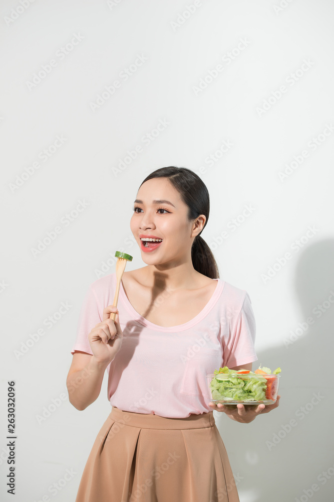 Portrait of a happy playful girl eating fresh salad from a bowl and winking isolated over white background Portrait of a happy playful girl eating fresh salad from a bowl and winking isolated over white background