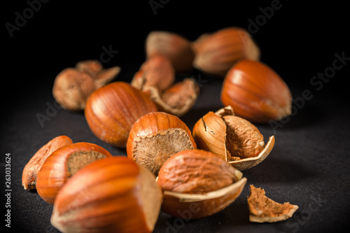 Some shelled hazelnuts with shell fragments around them, isolated on a black background