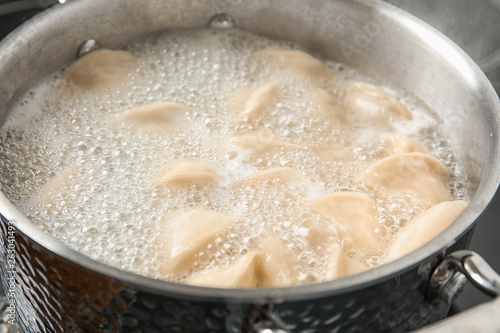 Closeup of metal stewpan with boiling water and dumplings. Home cooking