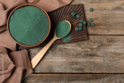 Flat lay composition with spirulina algae powder on wooden background, space for text photo