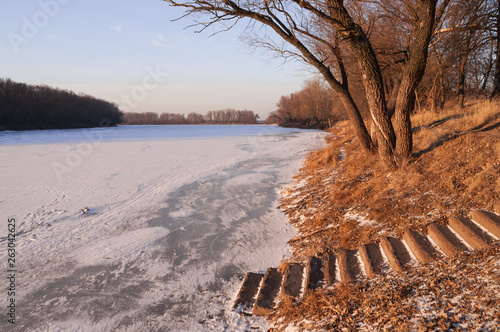 Frost river with snowand naked trees. Winter sunset in warm brown colors  photo