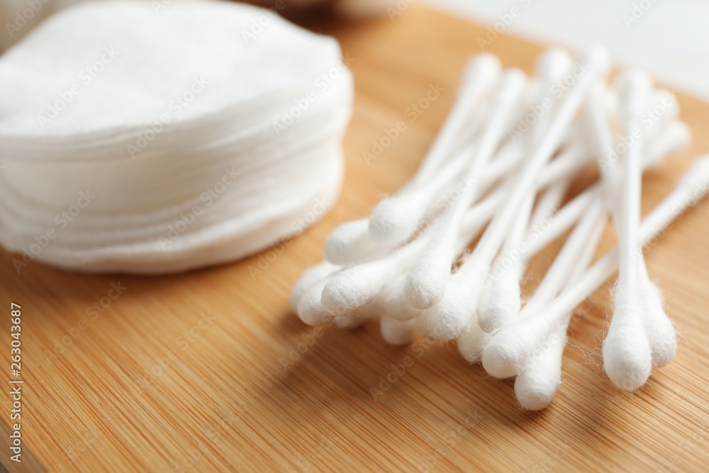 Cotton swabs and pads on wooden board, closeup Cotton swabs and pads on wooden board, closeup
