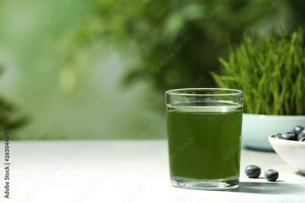 Glass of spirulina drink on table against blurred background, space for text Glass of spirulina drink on table against blurred background, space for text