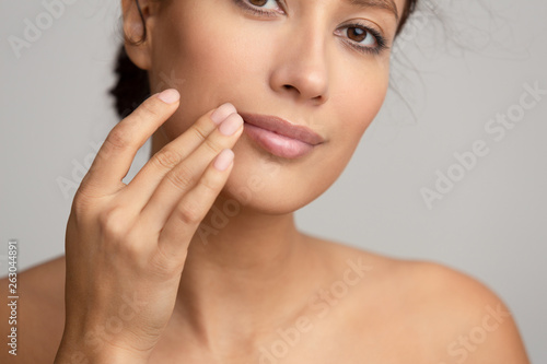 Natural beauty. Woman applying balsam  touching lips