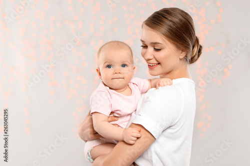 Portrait of happy mother with her baby against blurred lights. Space for text