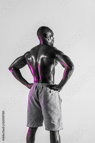 Young african-american bodybuilder training over grey background