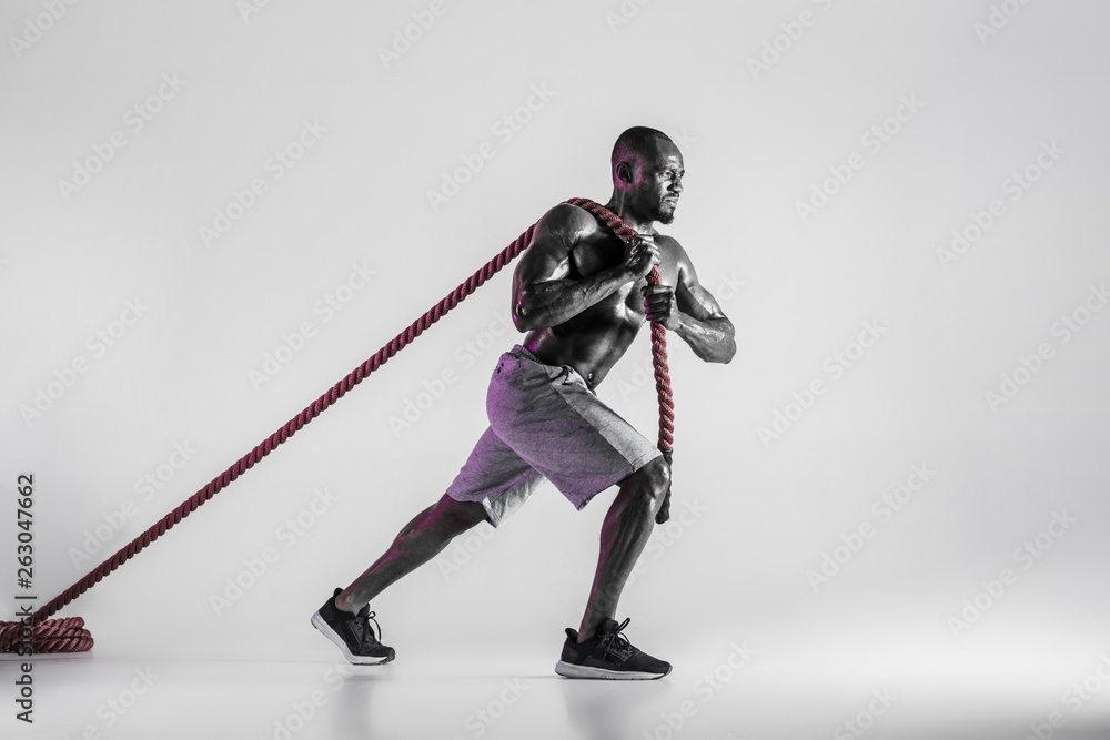 Young african-american bodybuilder training over grey background Young african-american bodybuilder training over grey background