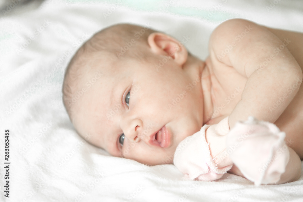 Closeup portrait of cute newborn baby lying down in the bed at home, smiling face, happy childhood, new life concept Closeup portrait of cute newborn baby lying down in the bed at home, smiling face, happy childhood, new life concept