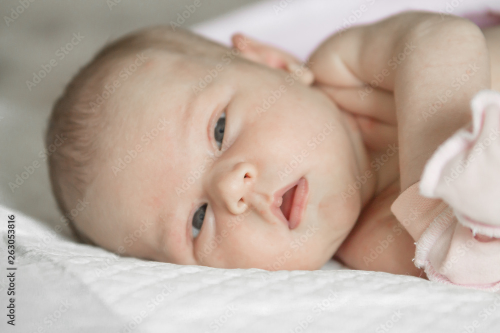 Closeup portrait of cute newborn baby lying down in the bed at home, smiling face, happy childhood, new life concept Closeup portrait of cute newborn baby lying down in the bed at home, smiling face, happy childhood, new life concept