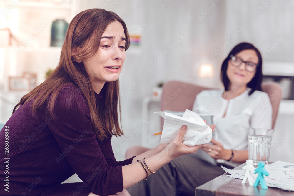 Crying upset young brown-haired lady going emotional during physiological therapy. Crying upset young brown-haired lady going emotional during physiological therapy.