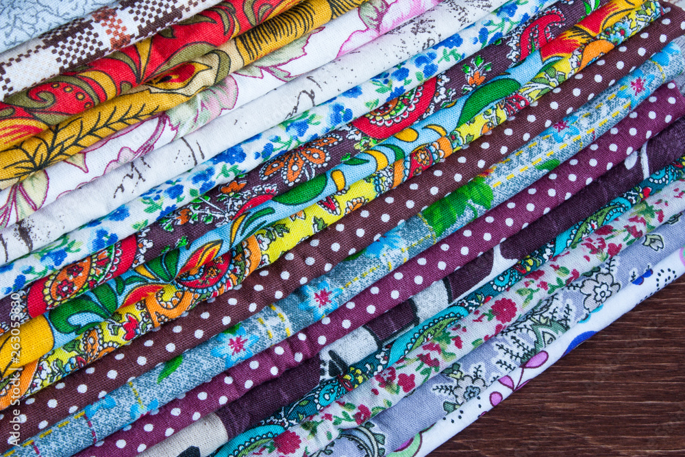 stack of multicolored fabrics on a wooden table