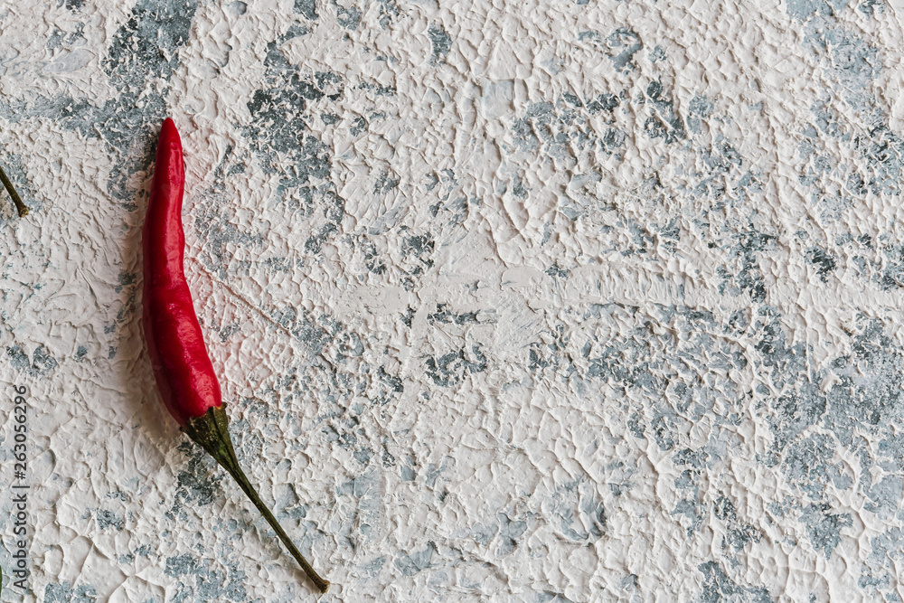 Textural blue and white background, on which lies a hot red pepper Textural blue and white background, on which lies a hot red pepper