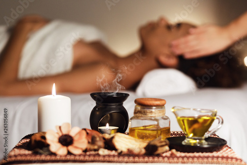 African woman having face massage, relaxing in spa salon