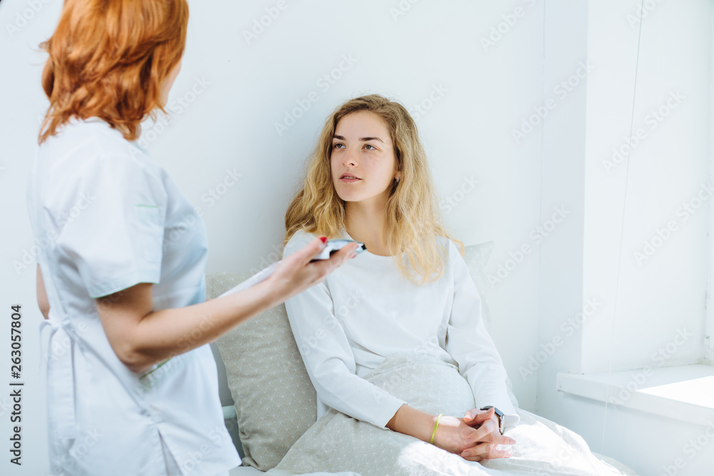 Female red hair doctor talking to patient about her history list in hospital room. Physical exam communication disease prevention ward round 911 prescribe remedy healthy lifestyle concept Female red hair doctor talking to patient about her history list in hospital room. Physical exam communication disease prevention ward round 911 prescribe remedy healthy lifestyle concept