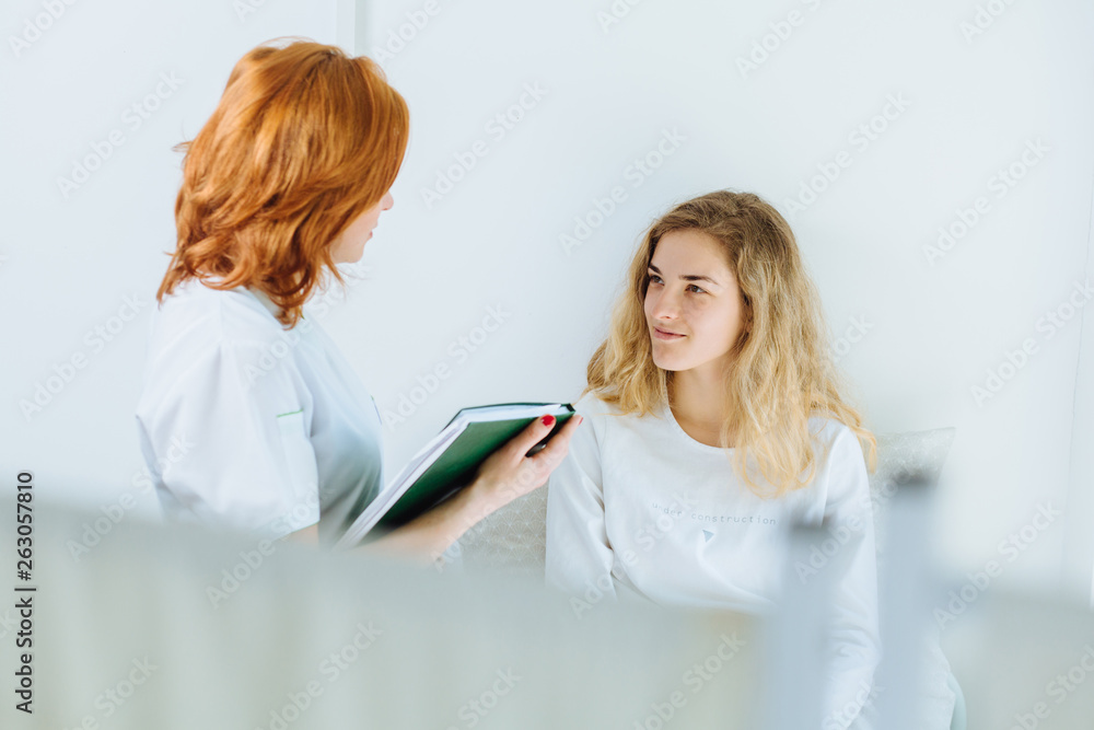 Yong beautiful blond ailing woman talking with her doctor in hospital room. Copy space Yong beautiful blond ailing woman talking with her doctor in hospital room. Copy space