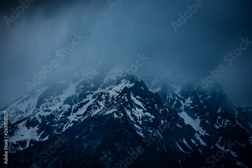Misty fog covered snowy mountain of the Sierra Nevada range. This moody capture shows the dark and majestic aura of the tall mountain peaks found in Eastern California near Mammoth Lake