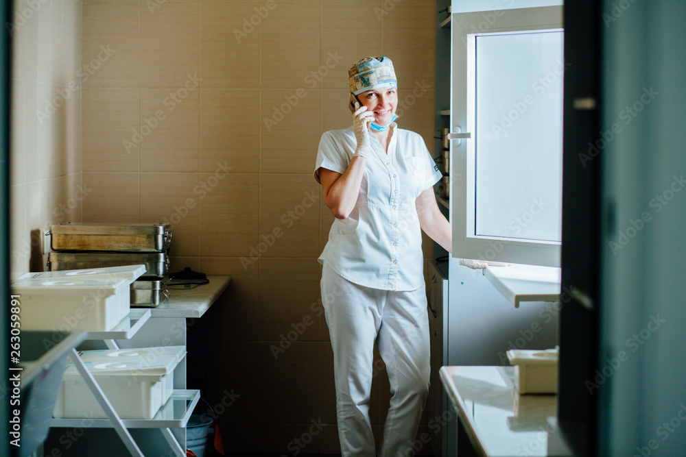 Fototapeta premium Female Surgeon Doctor Talking On Phone In Hospital Room For Equipment . Surgeon medic relaxing after for medical procedure