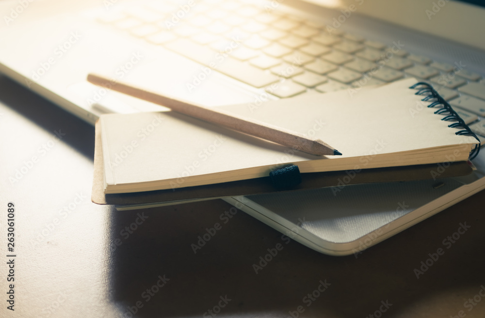 notebook and pencil place on laptop keyboard with morning light, vintage color effect notebook and pencil place on laptop keyboard with morning light, vintage color effect