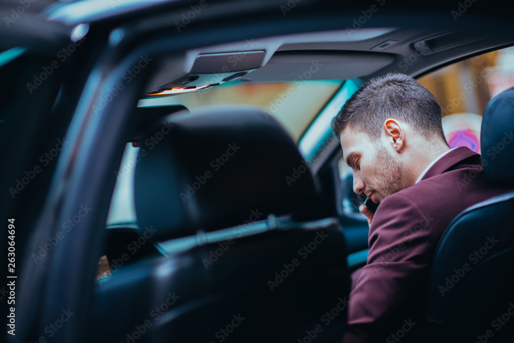 A serious businessman is having a conversation on his phone while looking sharp with his suit and tie. A serious businessman is having a conversation on his phone while looking sharp with his suit and tie.
