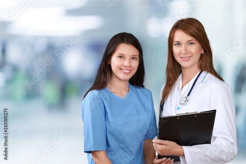 Attractive young female doctor with blurred hospital interior on background