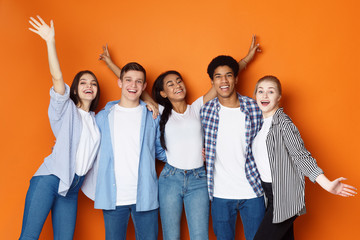 Students having fun over orange studio background