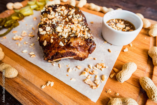 Close up board with pork ribs grilled with BBQ sauce, peanuts and jalapeno