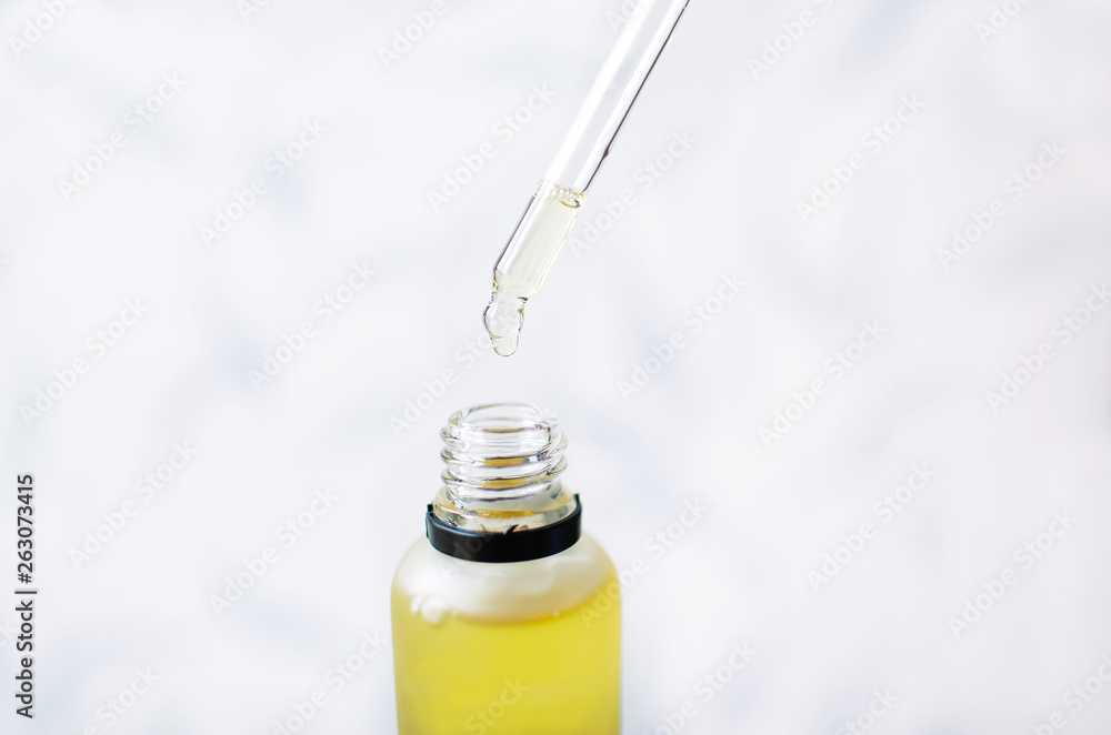 Oily yellow drop falls from cosmetic pipette on white background Oily yellow drop falls from cosmetic pipette on white background