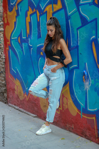 Trendy beautiful long haired young model posing on graffiti background